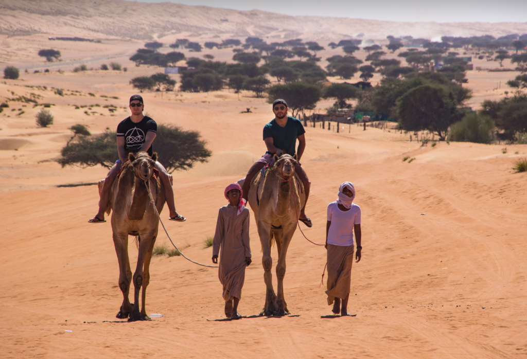 photo of men riding camels in the desert